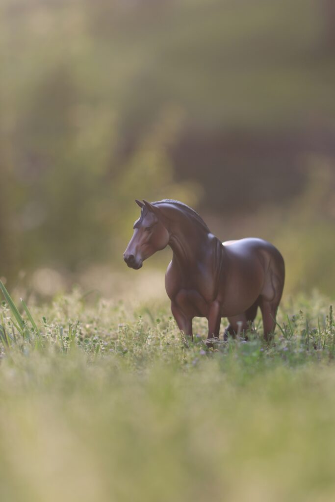 Model horse standing in green field.